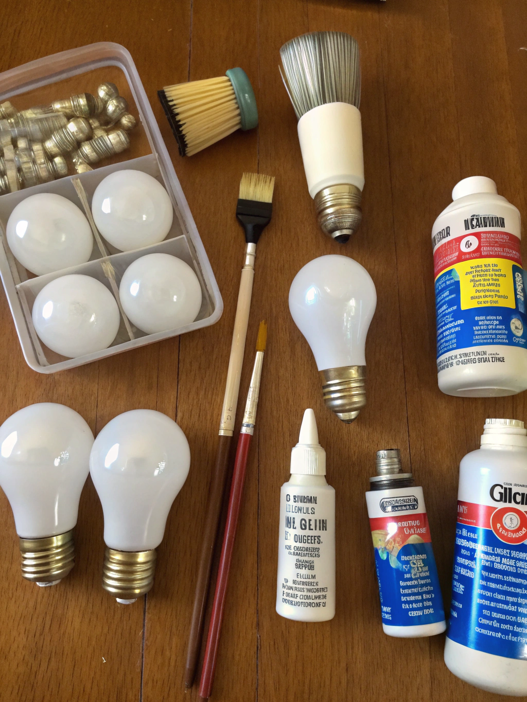 A collection of tools and materials for repurposing light bulbs, including pliers, safety glasses, and decorative elements.